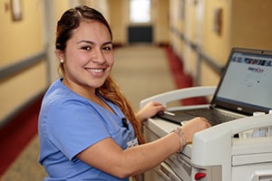 A caregiver at a nurse's cart in the hallway of Villa Las Palmas